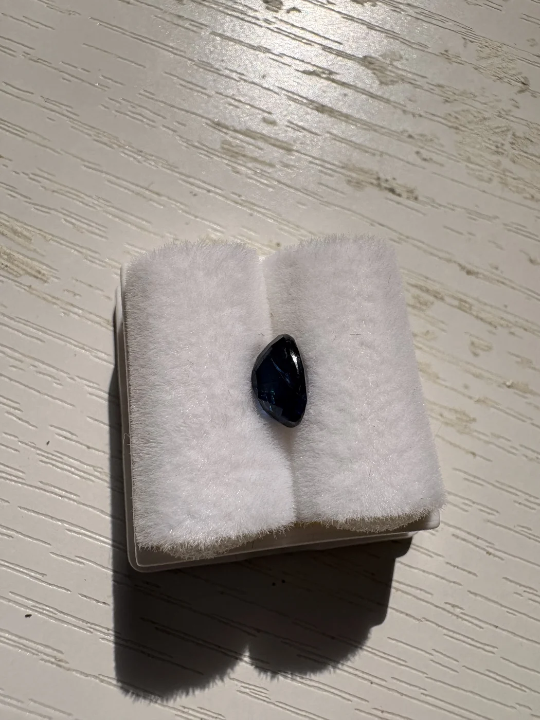 Side view of serial 108 oval blue sapphire in a display box