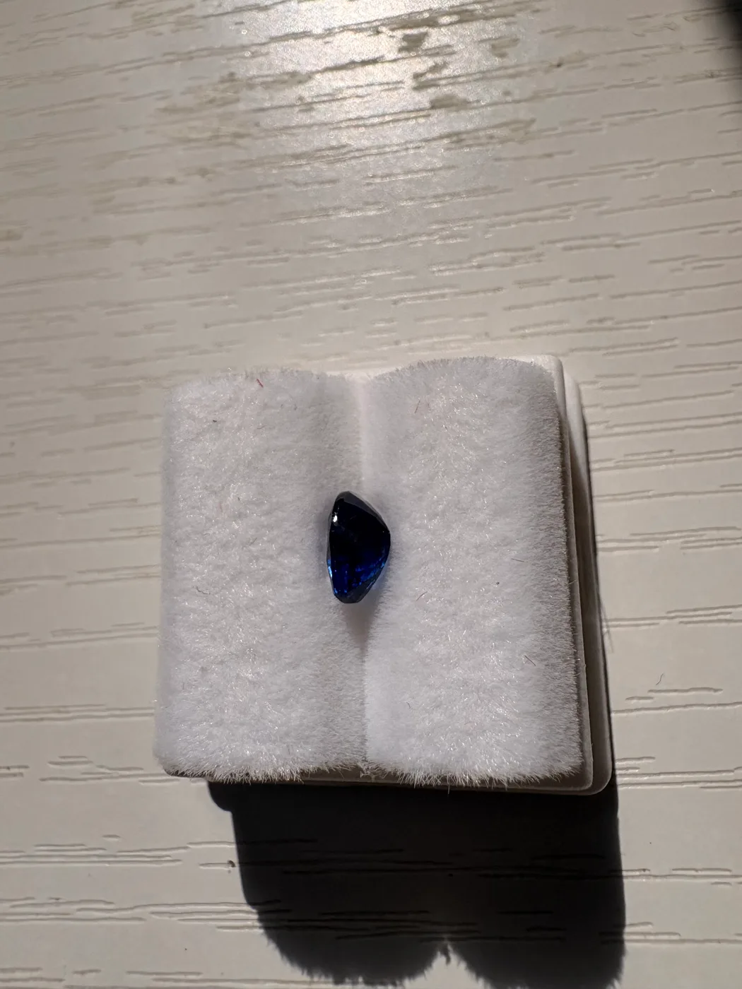 Side view of serial 110 oval Sri Lankan blue sapphire in a display tray