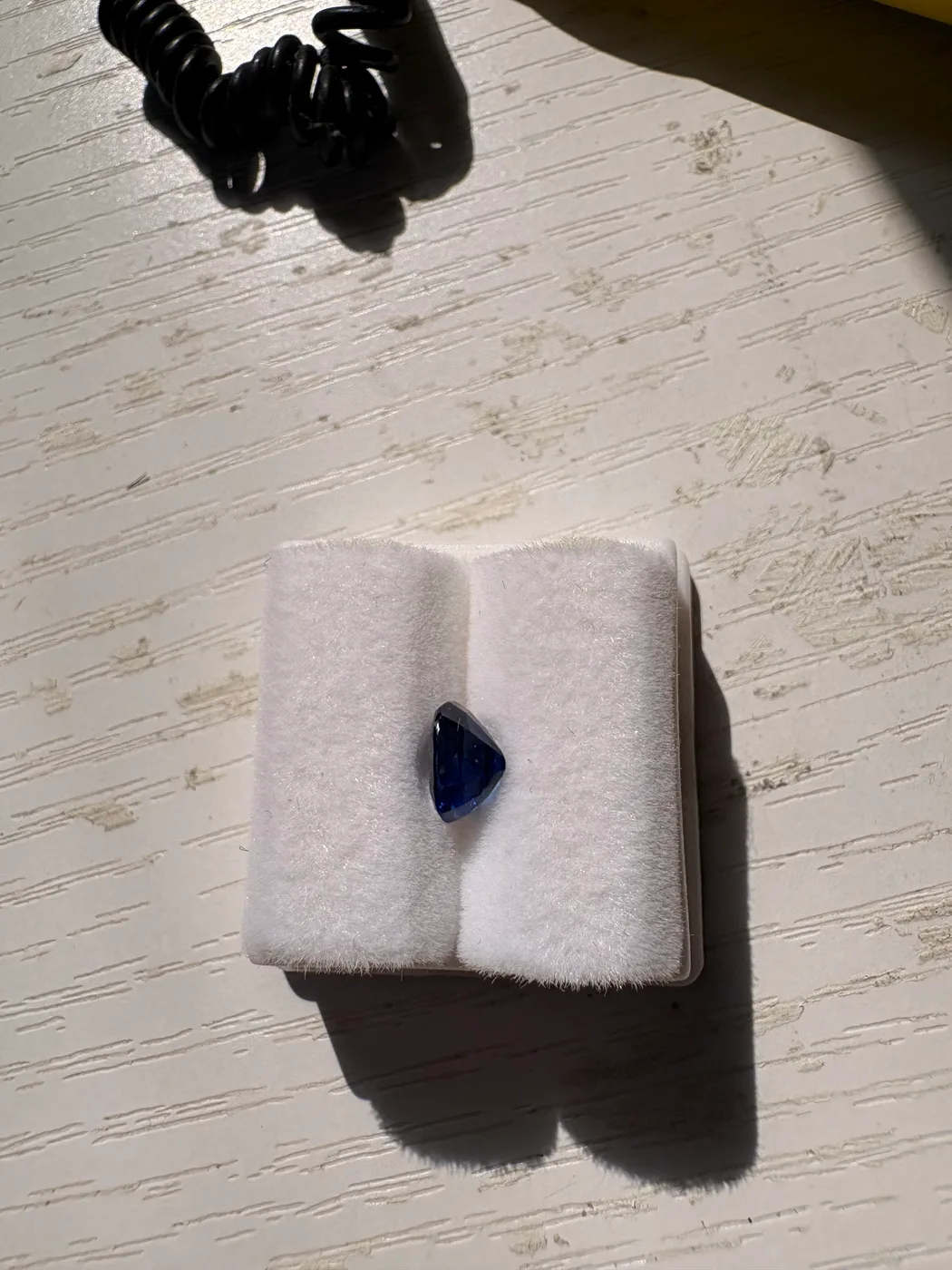 Side view of serial 111 oval Sri Lankan blue sapphire in a display tray