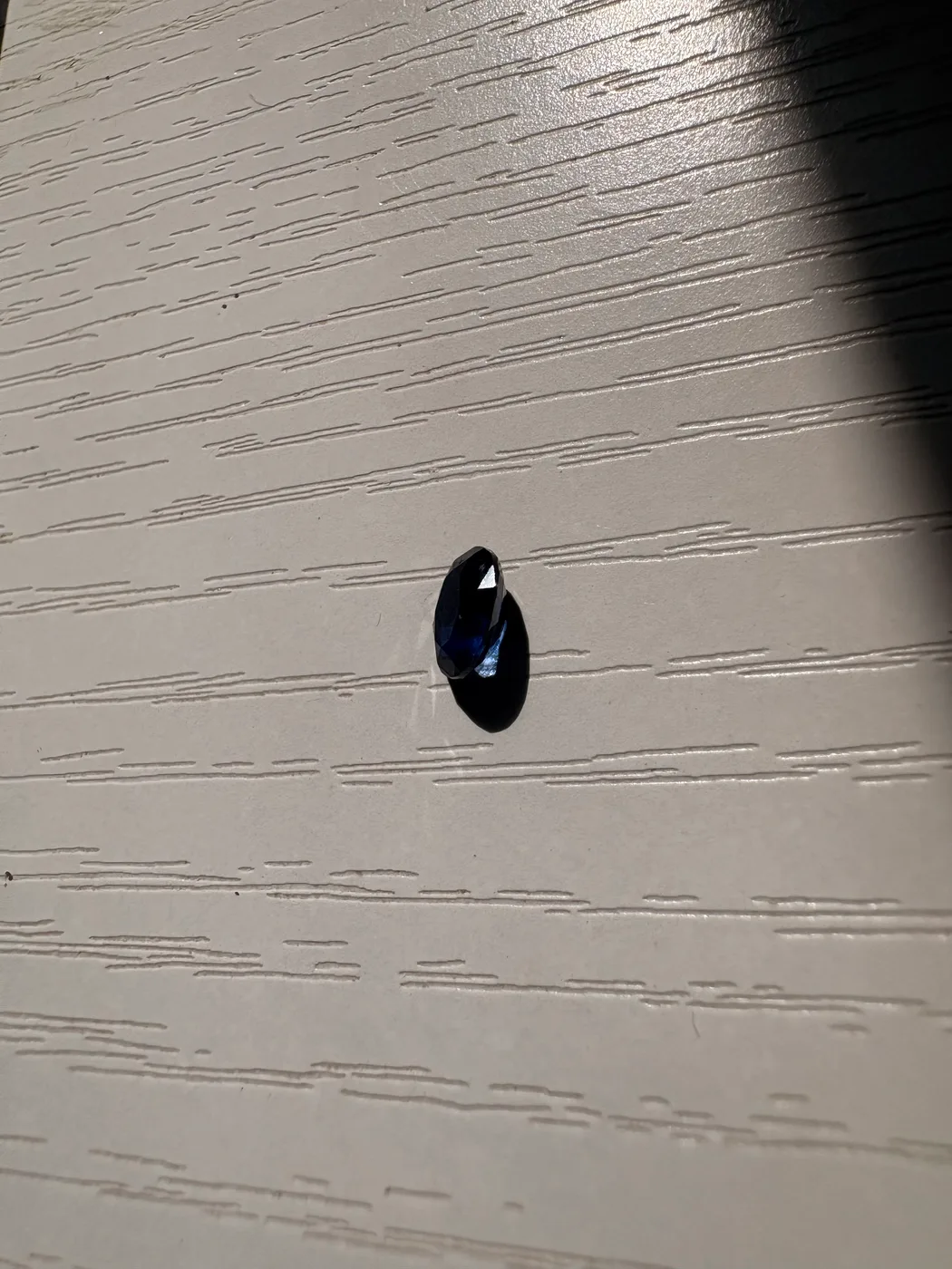 Side view of serial 112 oval Sri Lankan blue sapphire under light