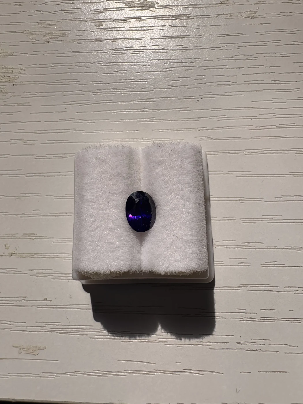 Serial 105 violetish-blue oval sapphire in a display box